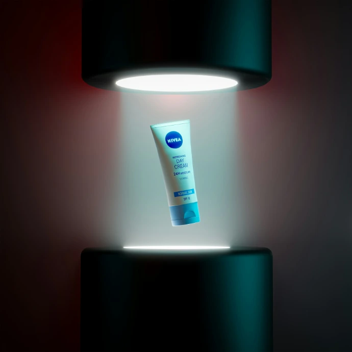 Nivea lotion tube illuminated between two dark cylinders